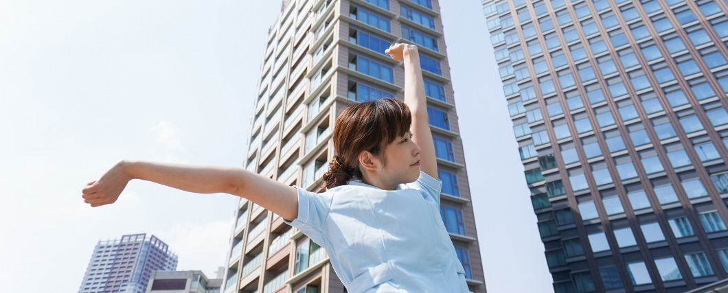 オフィスを背に伸びをする女性